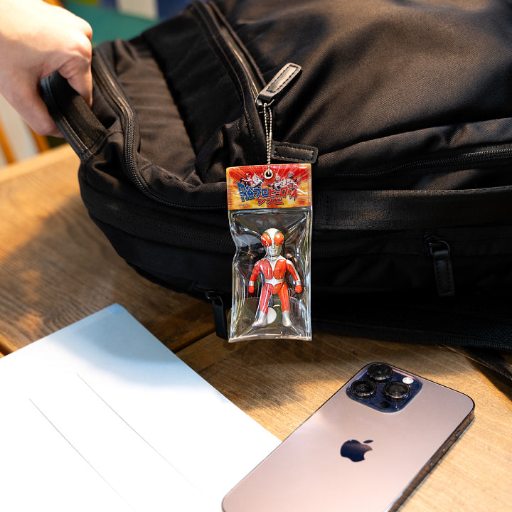 Fireman sofubi ball-chain mascot in miniature package attached to a black backpack