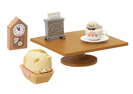 Sumikkogurashi Café miniature set with a wooden table, Neko in a basket, wall clock, napkin holder, and a character-topped coffee cup.