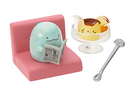 Sumikkogurashi Café miniature set with Tokage reading a newspaper on a pink chair, a character-themed pudding dessert, and a long spoon.