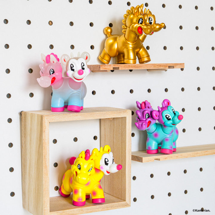 Four UMASHIKA figures displayed on wooden shelves against a white pegboard