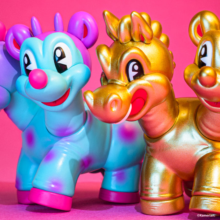 Close-up of Purple-Turquoise and Gold UMASHIKA figures on a pink background