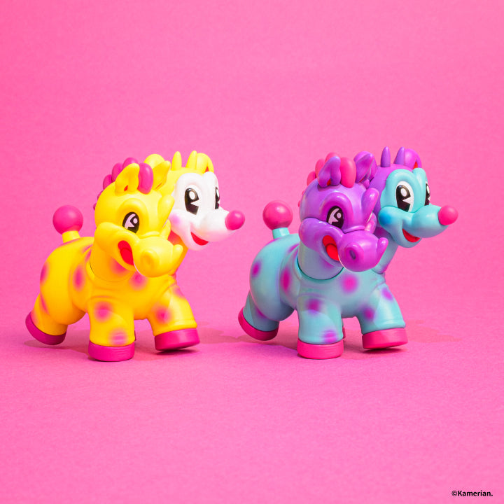 Side view of Yellow and Purple-Turquoise UMASHIKA figures on a pink background