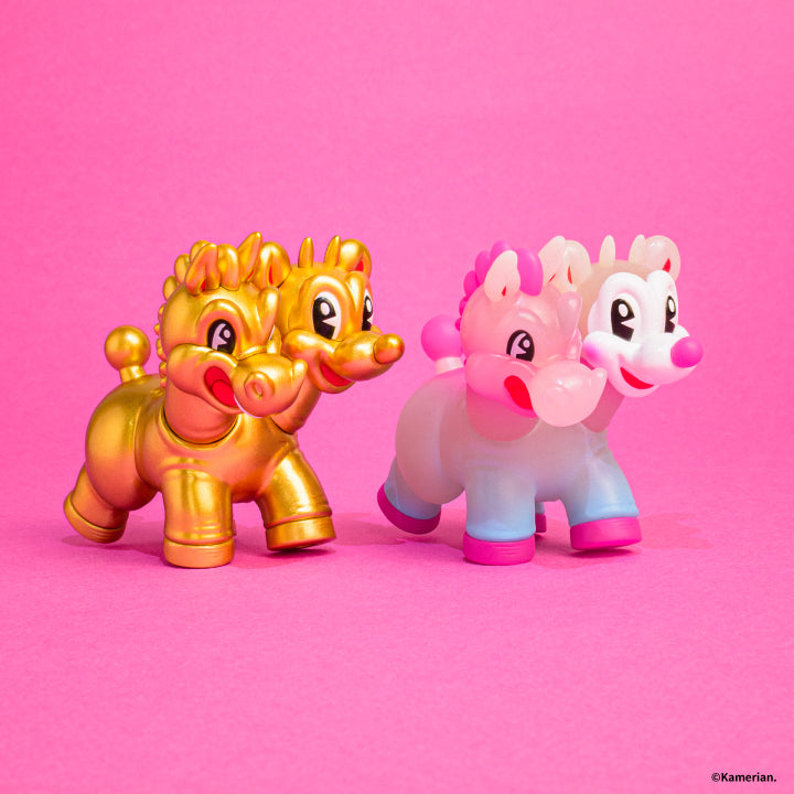Side view of Gold and Luminous UMASHIKA figures on a pink background