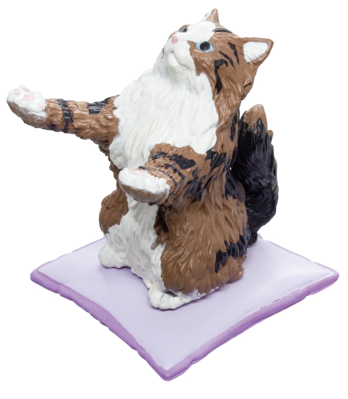 A figurine of a fluffy brown, white, and black cat sitting on a lavender rectangular base against a plain white background.
