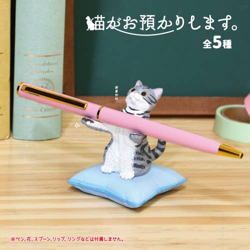 Cat-shaped pen holder with a pink pen on a wooden surface